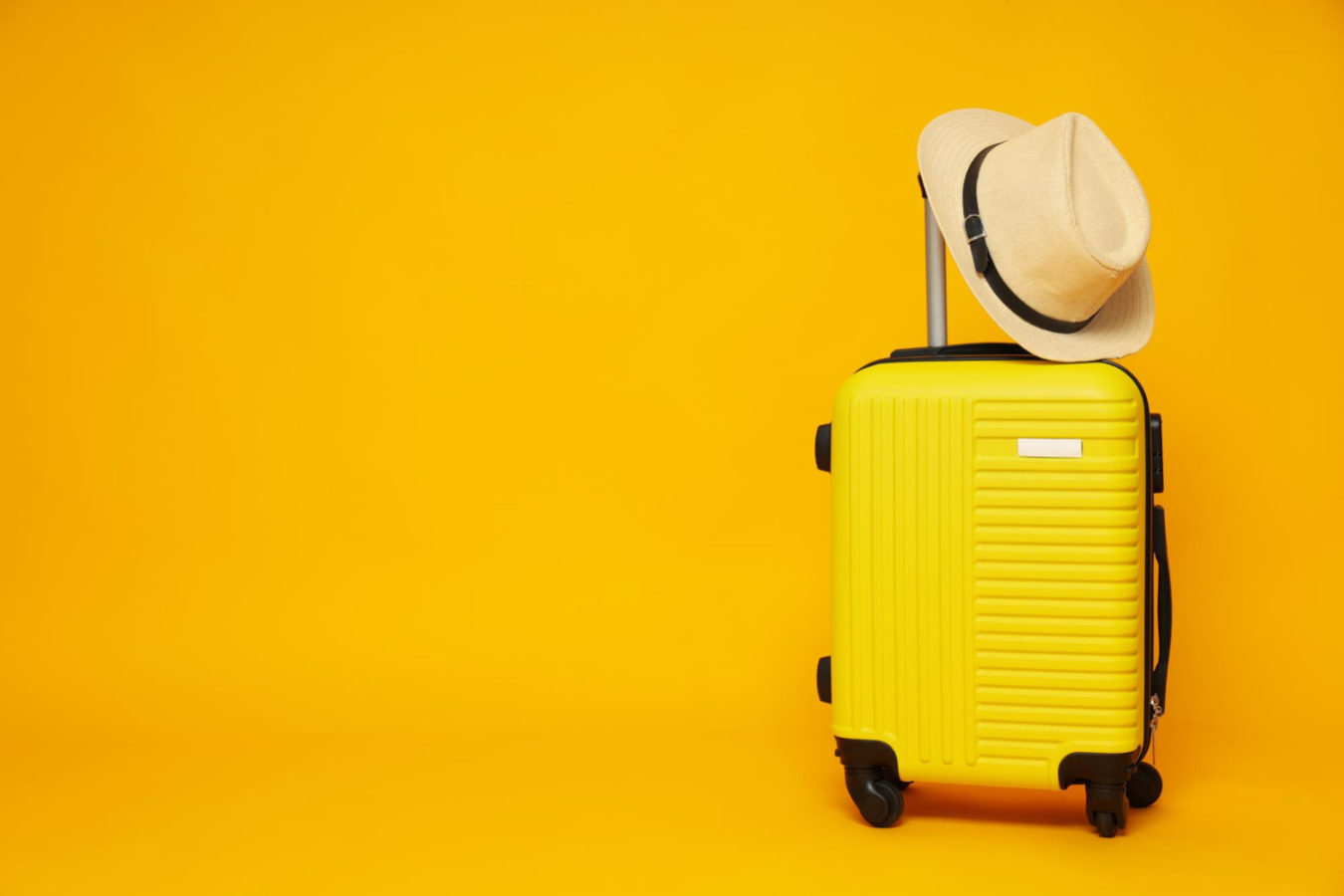 imagem mostra uma mala amarela e um chapéu, ilustrando feriados nacionais