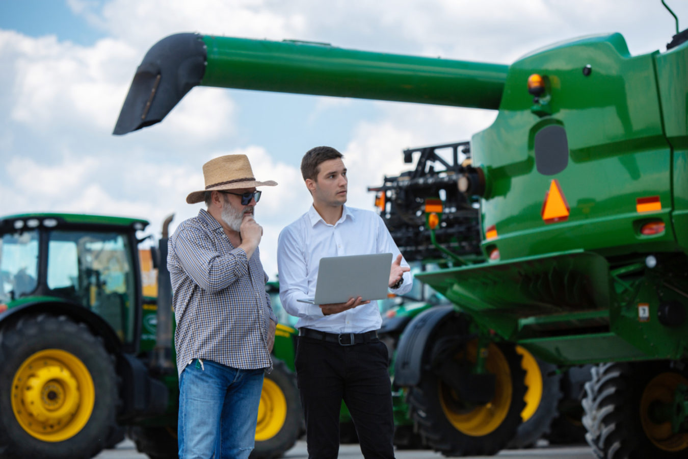 imagem monstra duas pessoas conversando em frente a uma máquina agrícola para ilustrar um artigo sobre engenharia agrícola