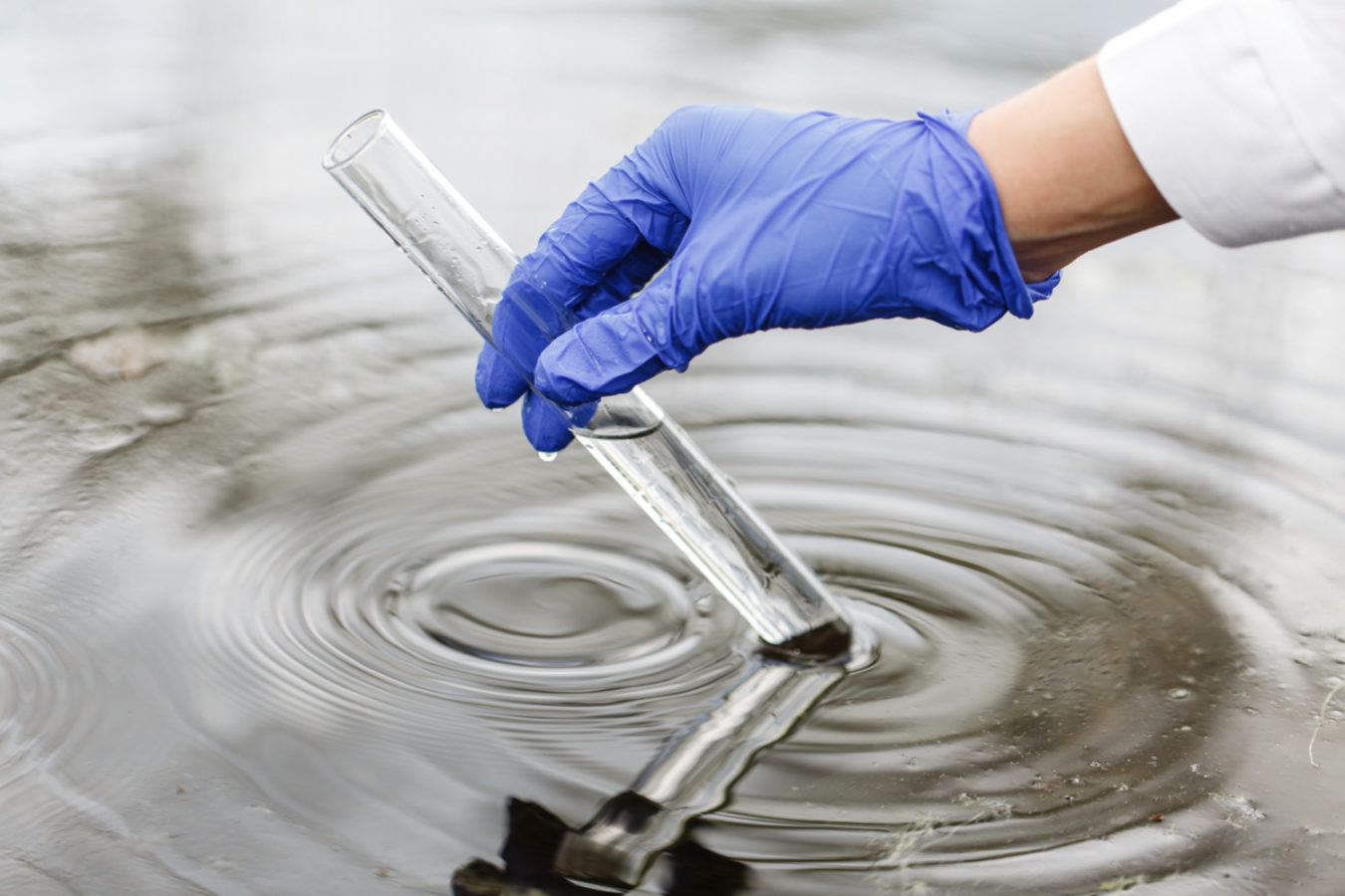 imagem mostra pesquisador com tubo de ensaio coletando água para um artigo sobre engenharia sanitária