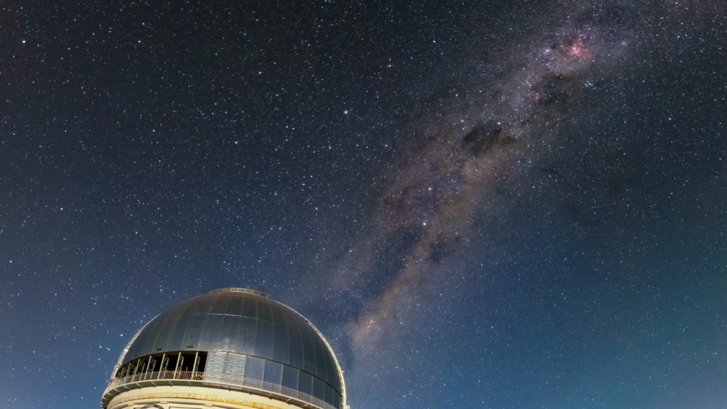 A Via Láctea iluminando o céu acima do Telescópio Víctor M. Blanco de 4 metros, utilizado na descoberta da galáxia, no CTIO - CTIO/NOIRLab/NSF/AURA/D. Munizaga.